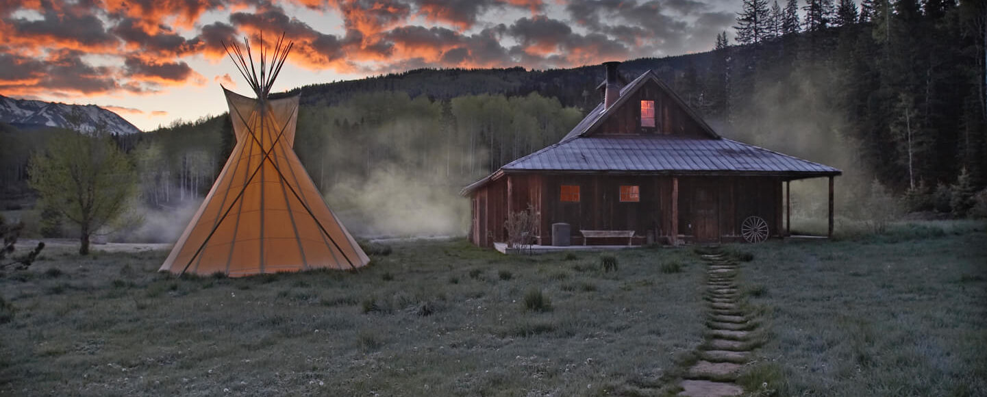 Tipi and bathhouse cabin at dawn