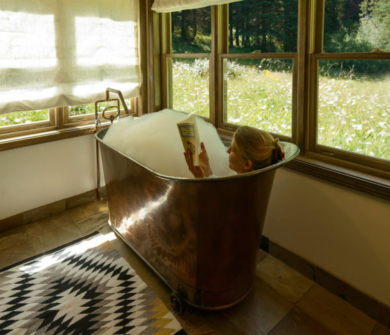 Guest reading a book while bathing in a cabin